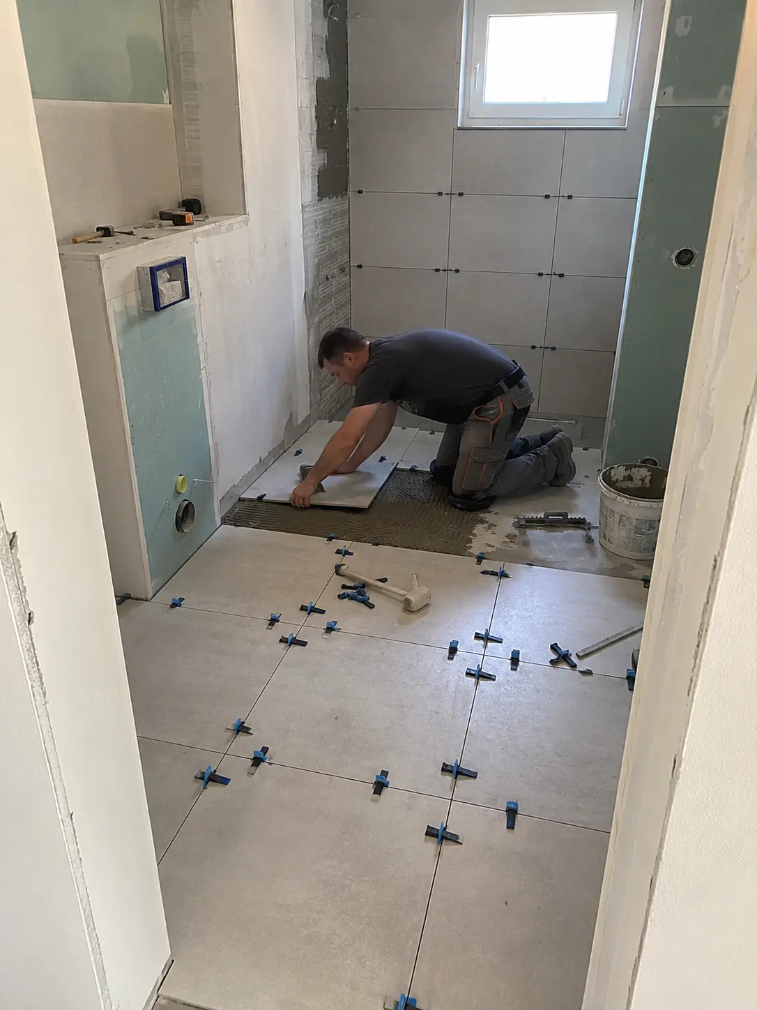Fliesenleger beim Verlegen von Bodenfliesen im Badezimmer in Schwäbisch Hall