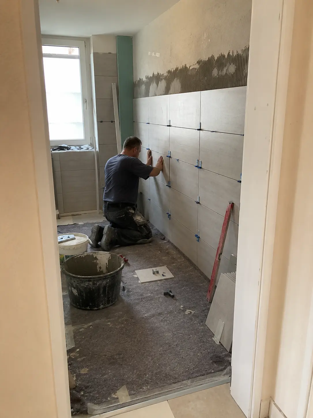 Fliesenleger beim Verlegen von Wandfliesen im Badezimmer in Schwäbisch Hall