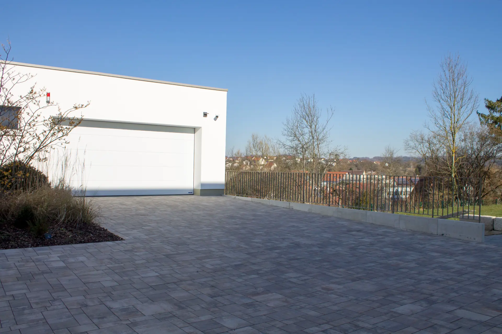 Fertig gepflasterter Hof aus Betonpflaster vor einer weißen Garage