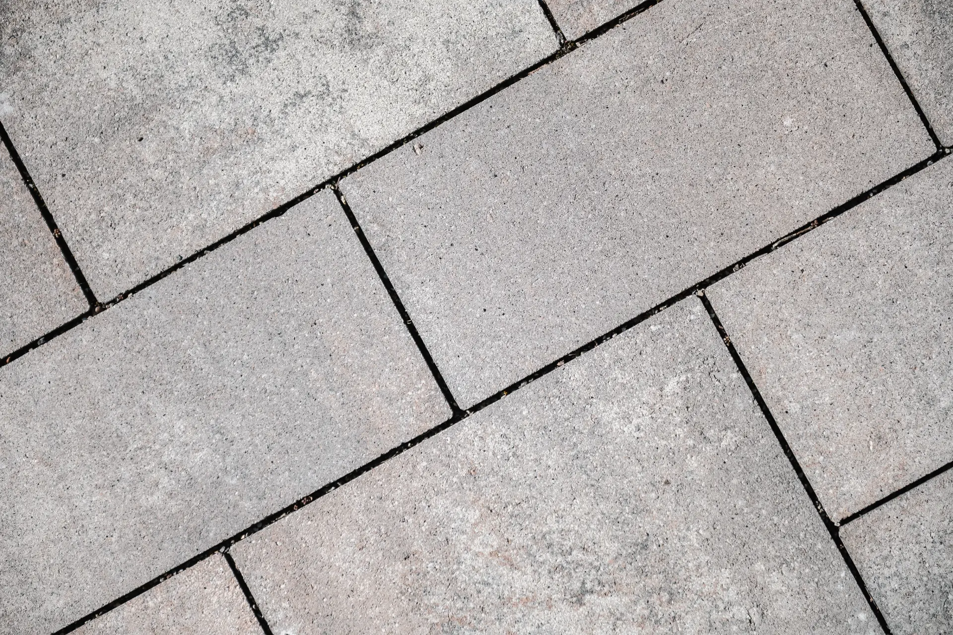 Detail von diagonal verlegten grauen Pflastersteinen mit sauberer Fuge