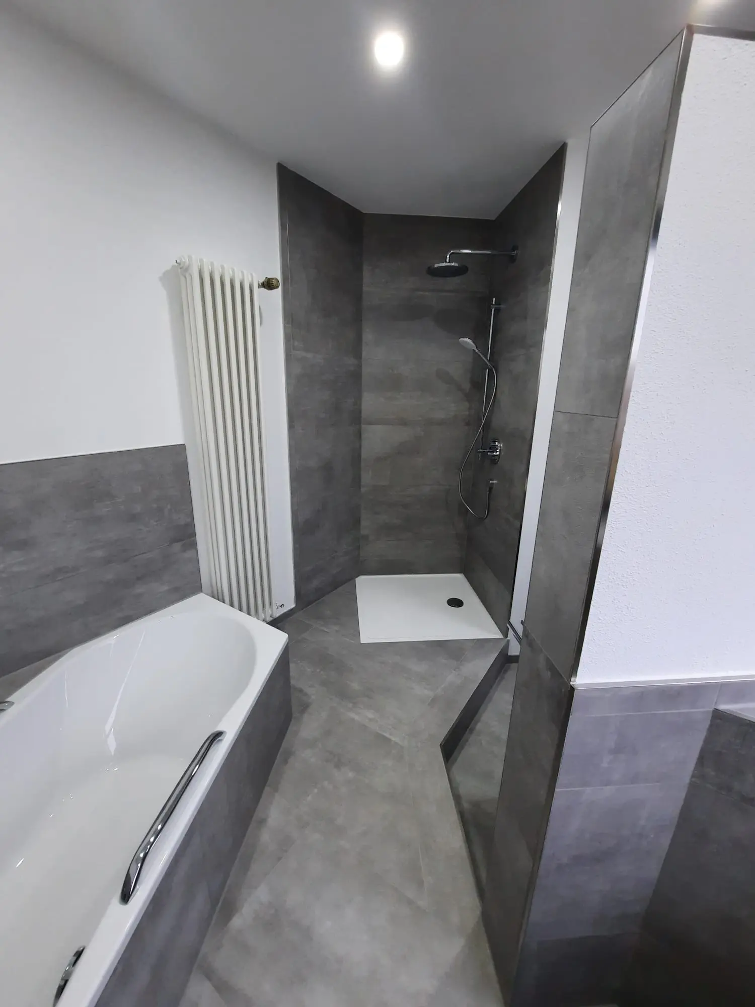 Fertiges Bad mit bodengleicher Dusche, Einbauwanne und grauen Betonoptikfliesen in Schwäbisch Hall