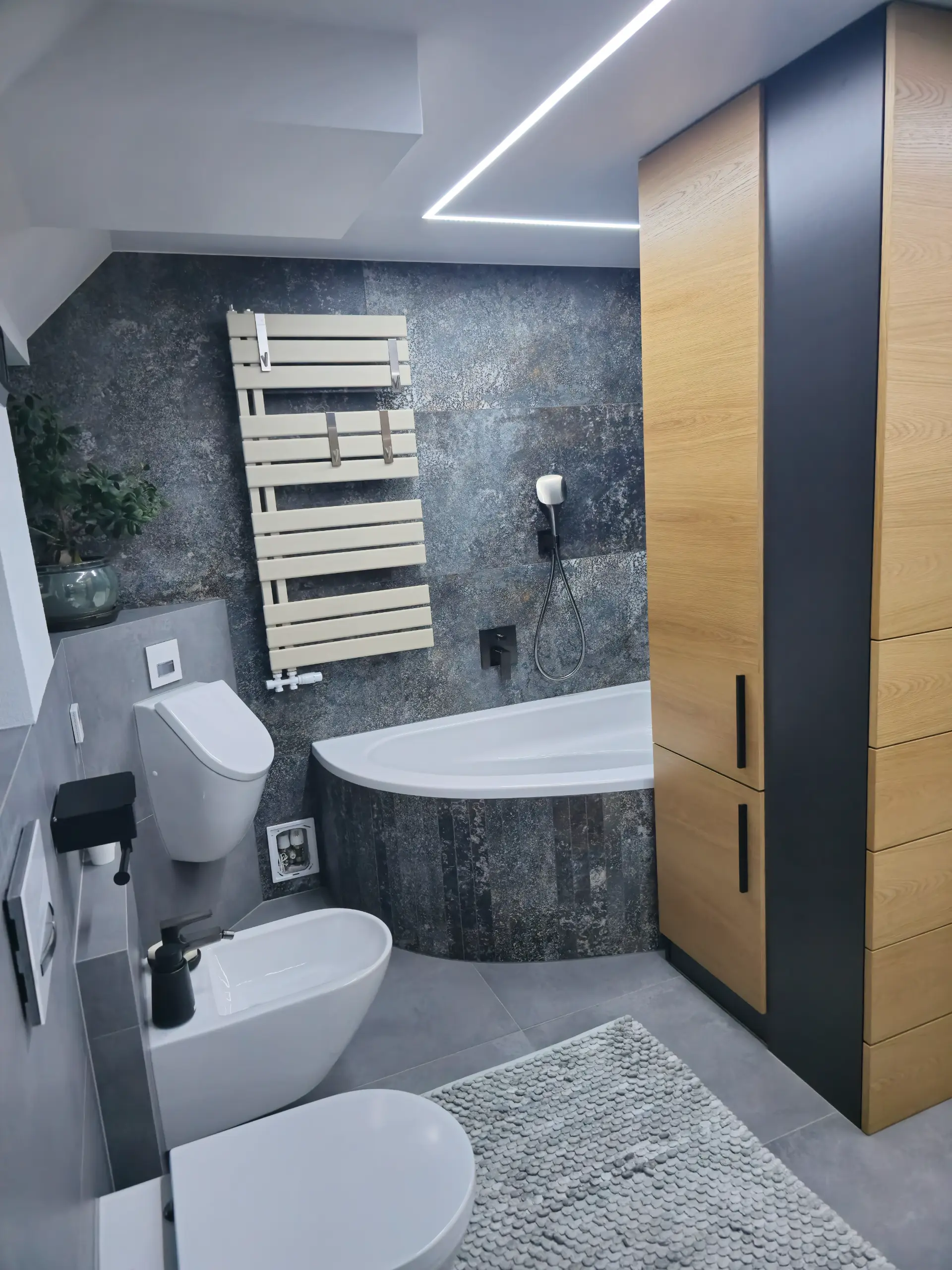 Fertiges Bad mit Eckbadewanne, WC und Bidet in dunkler Steinoptik