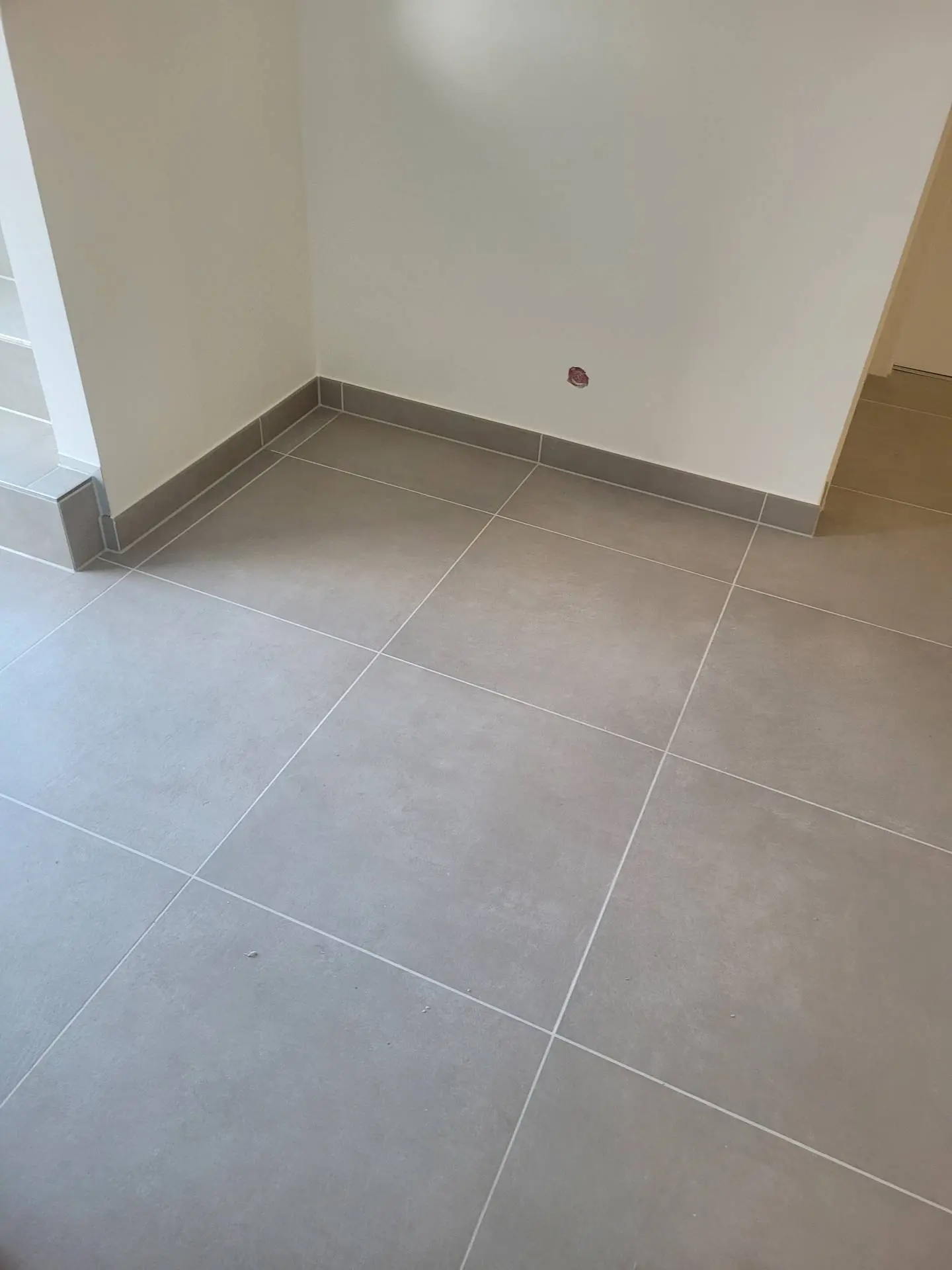Großformatige graue Bodenfliesen mit passender Sockelleiste in einem sanierten Raum in Schwäbisch Hall