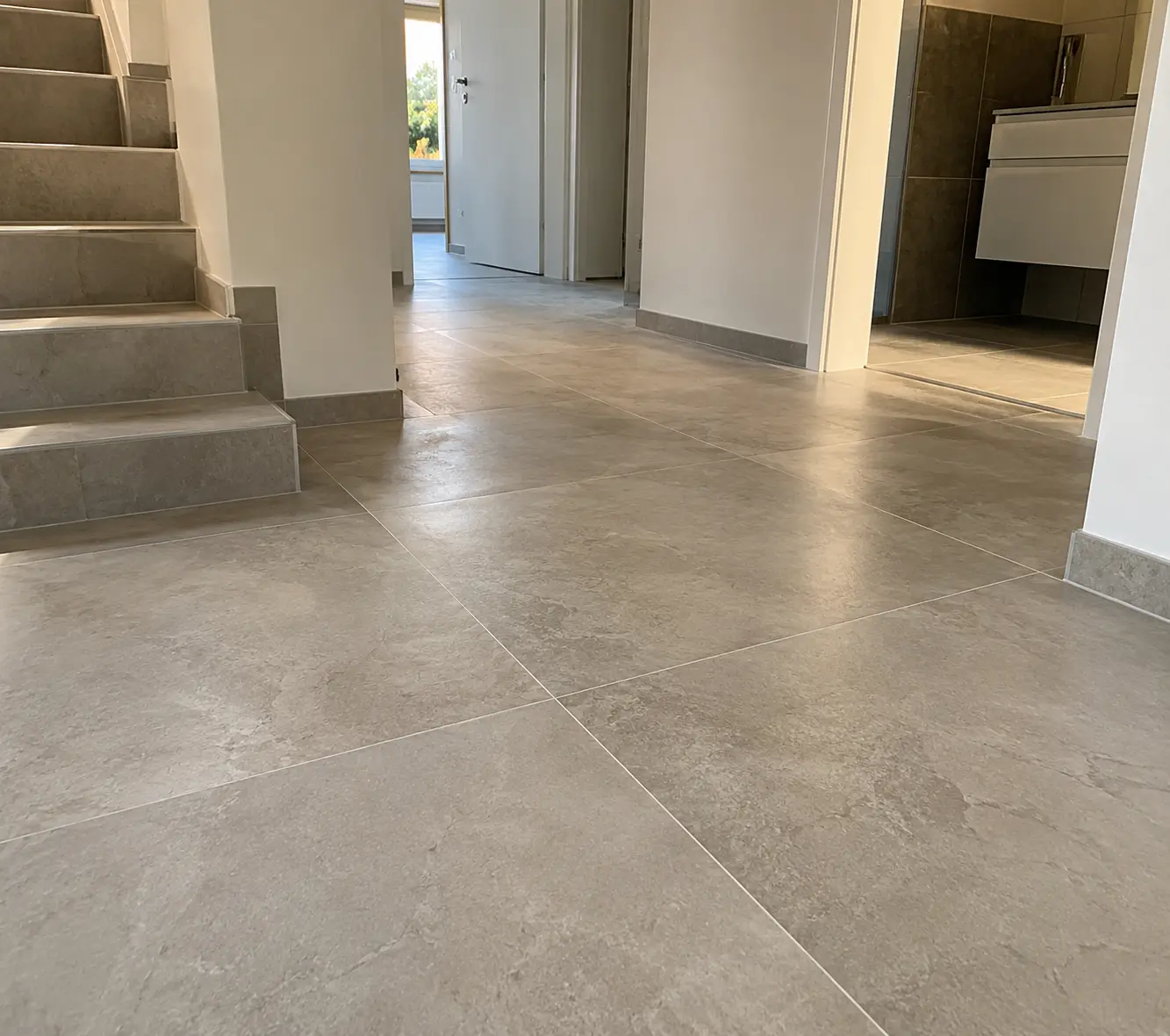 Großformatige Bodenfliesen in Flur und Treppe eines sanierten Hauses