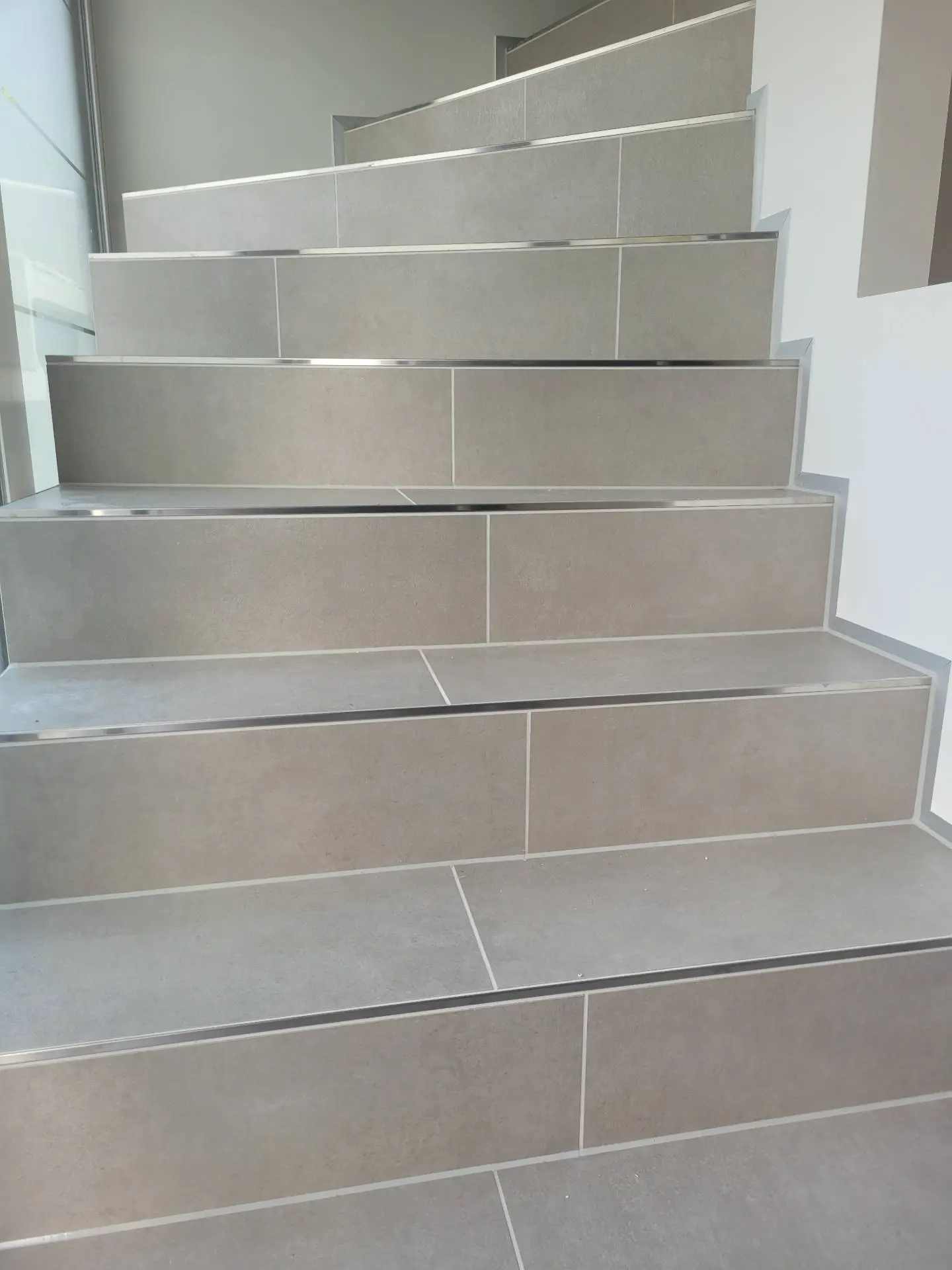 Treppe mit gefliesten Stufen und Setzstufen und Kanten aus Edelstahl