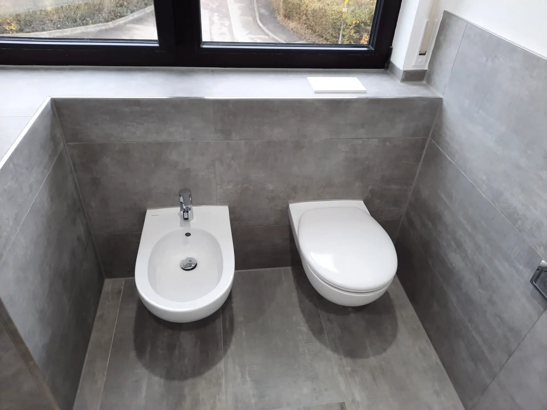Wandhängendes WC und Bidet vor Großformatfliesen in Betonoptik
