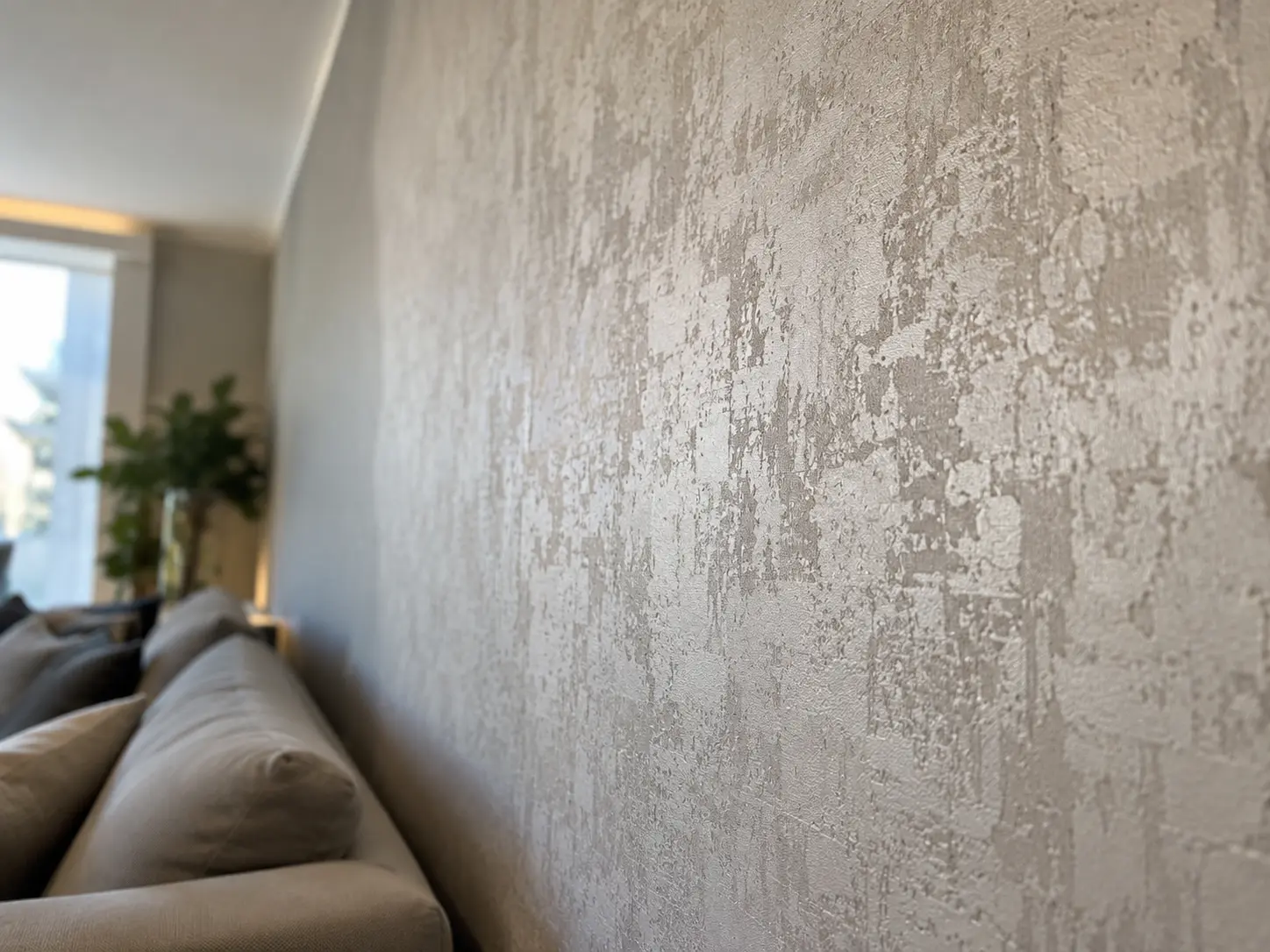 Wohnraum mit Strukturtapete in Steinoptik an der Wand und einem Sofa davor