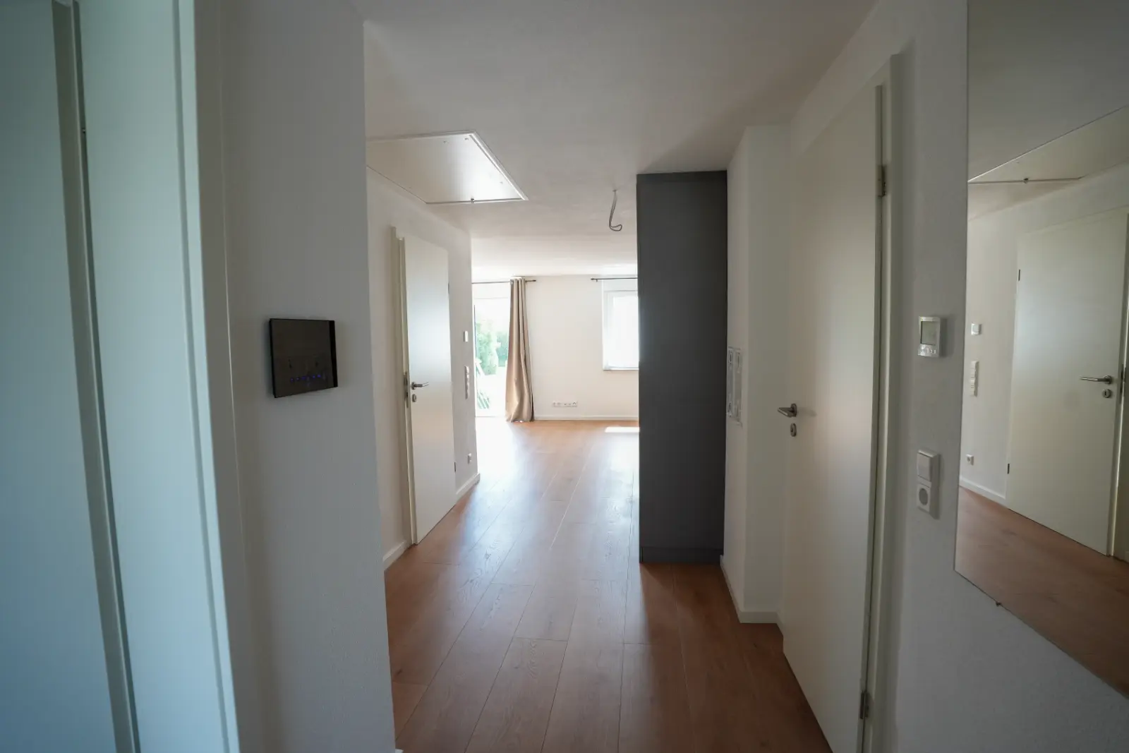 Sanierter Flur mit weißen Innentüren, Holzboden und Videosprechanlage
