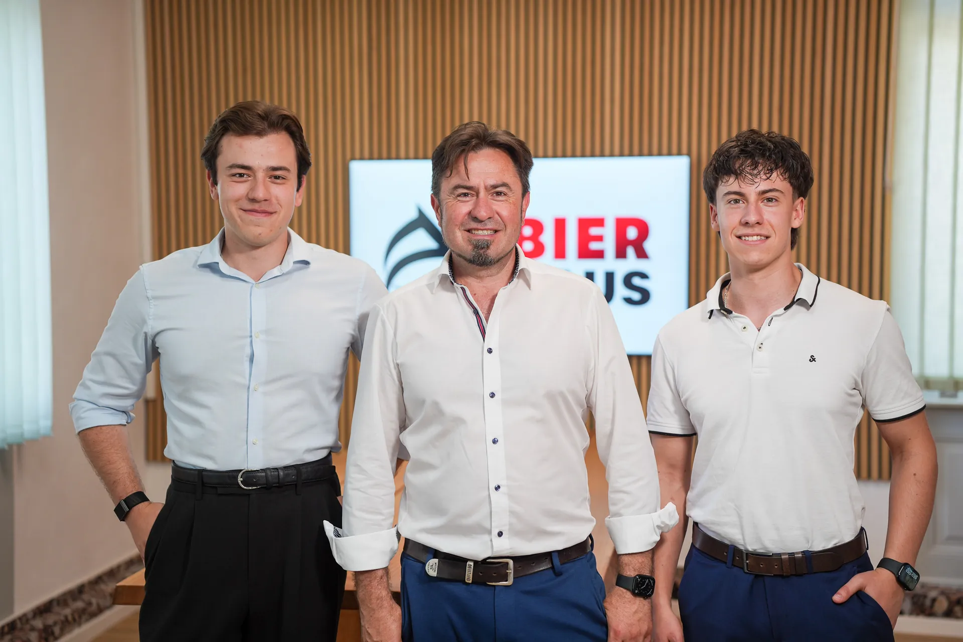 Dominik, Eduard und David Bier im Büro von Bier Haus in Schwäbisch Hall vor dem Firmenlogo