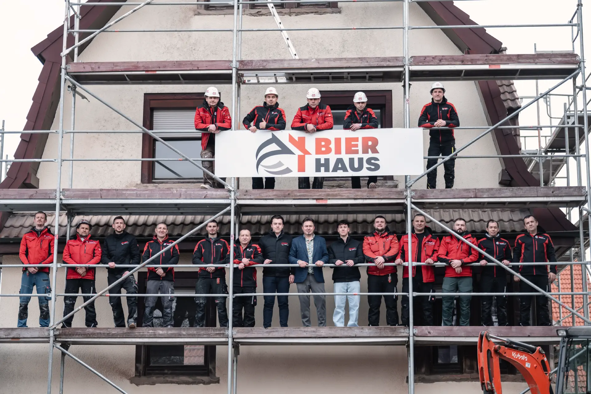 Das Team von Bier Haus auf dem Gerüst hält das Firmenschild
