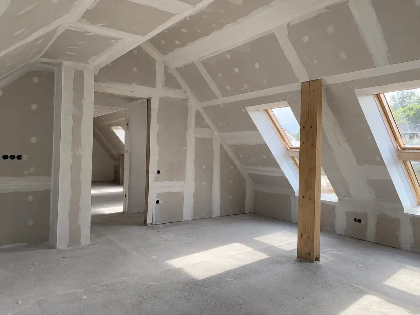 Dachgeschoss mit gespachtelten Gipskartonwänden, Dachfenstern und Holzstütze in Schwäbisch Hall
